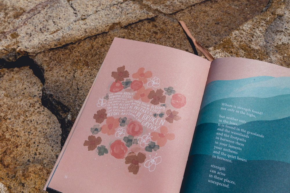[Image Description: book open and lying flat on a sand coloured stone. The pages have pink and blue watercolour artwork paintings of mountains and flowers, and white writing with Morgan Harper Nichols poetry.]