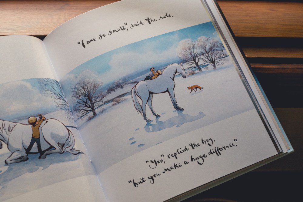 [Image Description: The Boy, The Mole, The Fox and the Horse: The Animated Story by Charlie Mackesy book held by a white hand, against a time ledge. The book is open to a page of a snow covered field with trees, and a boy lying on a horse's back holding up the mol. The text says "I am so small" said the mole. "yes" replied the boy, "but your make a huge difference".]