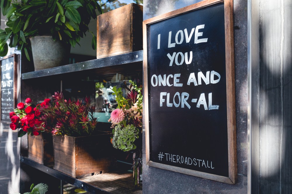 [Image Description: Blackboard sign with a shelf of bunches of flowers next to it. The sign says "I love you once and flor-al".]